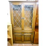 A 3' 4" Old Charm polished oak display cabinet with shelves enclosed by a pair of leaded glazed