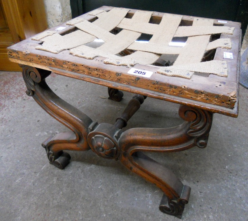 An early Victorian mahogany X-framed stool, with flowerhead bosses and acanthus scroll terminals -