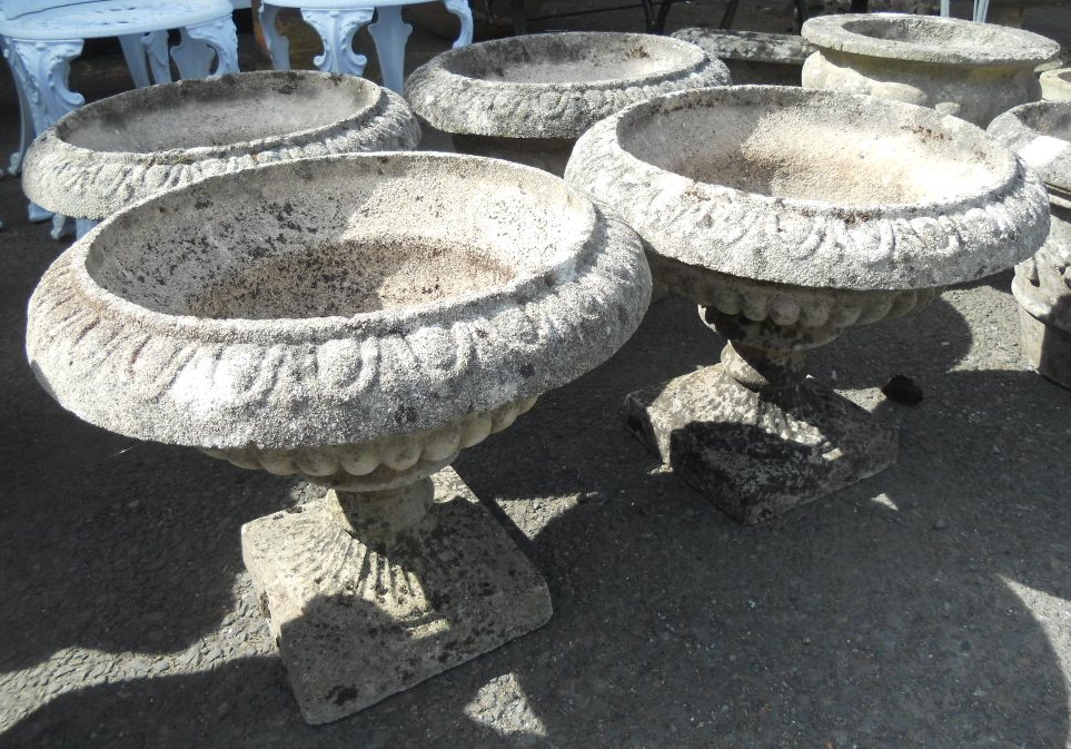 A set of four 15" high reconstituted concrete pedestal planters with egg and dart decoration to