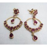 A pair of unmarked Edwardian style open loop ear-rings, set with rubies in various cuts