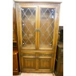 A 3' 4" Old Charm polished oak display cabinet with shelves enclosed by a pair of leaded glazed