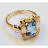 A marked .750 ornate panel ring, set with central cornflower blue stone