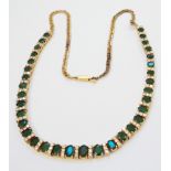 An 18ct. gold necklace, set thirty four graduated oval emeralds interspersed with multiple small