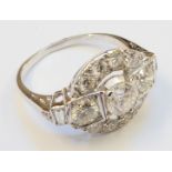 An Art Deco style 18ct. white gold ring, with open set central diamond, flanking diamonds and