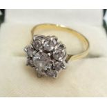 An 18ct. gold flowerhead ring, set with large central diamond within an eight stone border
