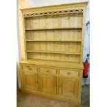 A 5' 2" waxed pine dresser, with moulded and pierced cornice to three shelf open plate rack, over