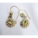 A pair of 9ct. gold ear-rings, set with central peridot within a seed pearl border