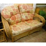 A cane and wicker framed conservatory suite, comprising a two seater settee and pair of armchairs
