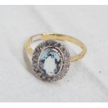 An 18ct. gold ring, set with central oval aquamarine within a diamond encrusted border