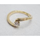 A 14ct. gold diamond solitaire cross-over ring