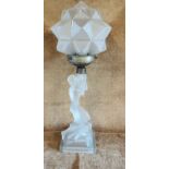 An Art Deco opaque glass lamp in the form of a kneeling lady, with a polygonal shade