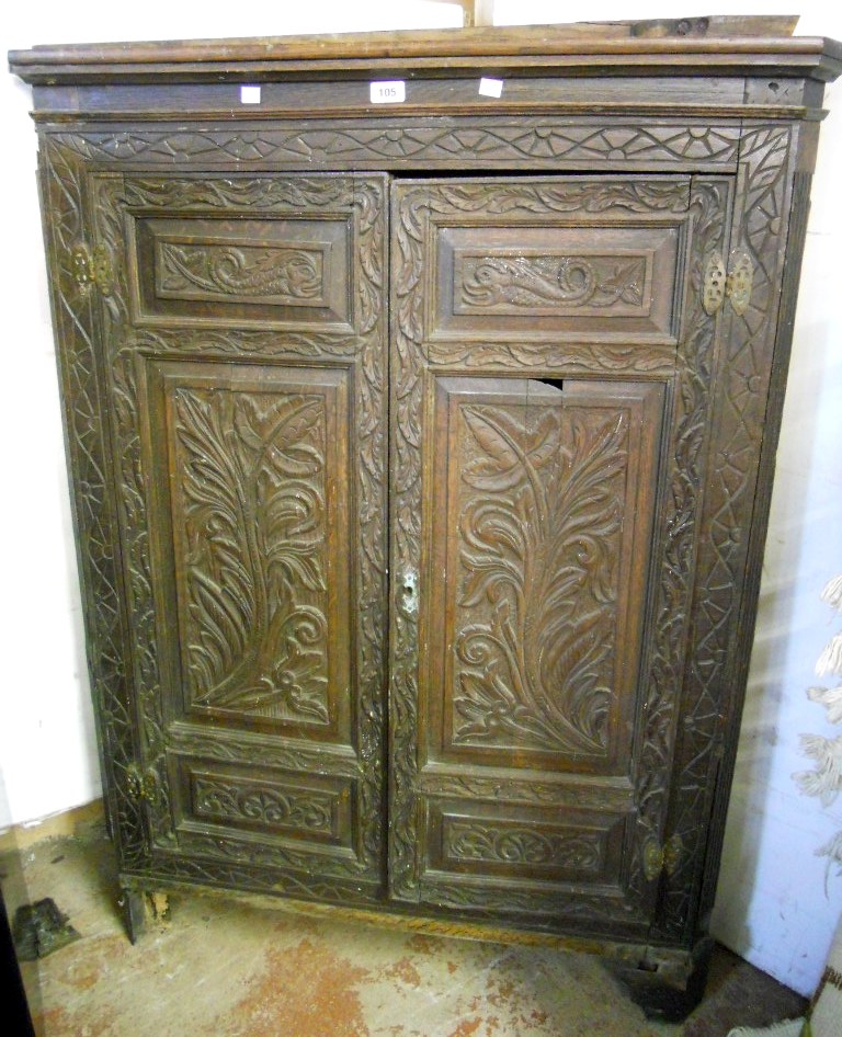 A 3' 3" antique continental carved oak corner cupboard, with scalloped shelves enclosed by a pair of