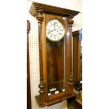 A stained walnut cased Vienna style wall clock with decorative dial, visible pendulum and twin