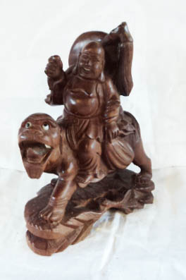 A carved hardwood figure of Buddha riding a stylised tiger