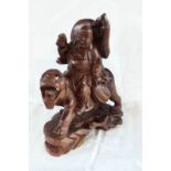A carved hardwood figure of Buddha riding a stylised tiger