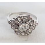 An 18ct. white gold Art Deco style ring, set with central stone on a diamond encrusted border with