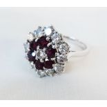 An unmarked 18ct. white gold ring, set with a band of rubies and diamond cluster