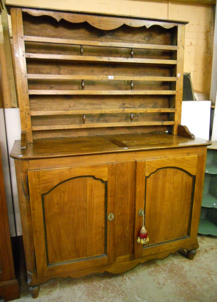 A 5' 2" continental walnut and stained mixed wood two part dresser, with three shelf open plate rack