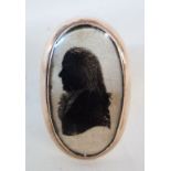 An antique yellow metal ring with large oval panel featuring a painted silhouette profile portrait