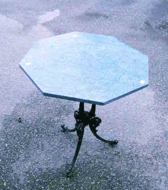 A 24" octagonal green marble topped table, set on a cast iron base with pillared column and