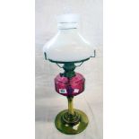 A Victorian brass table oil lamp with cranberry glass reservoir, slender chimney and milk glass
