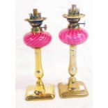 A pair of turn of the Century oil lamps, with pink twisted glass reservoirs and brass candlestick