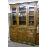 A 5' oak two part bookcase cabinet with shelves enclosed by triple bevelled glazed panel doors, over