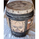 A tribal wooden drum with pegged skin and carved mask decoration