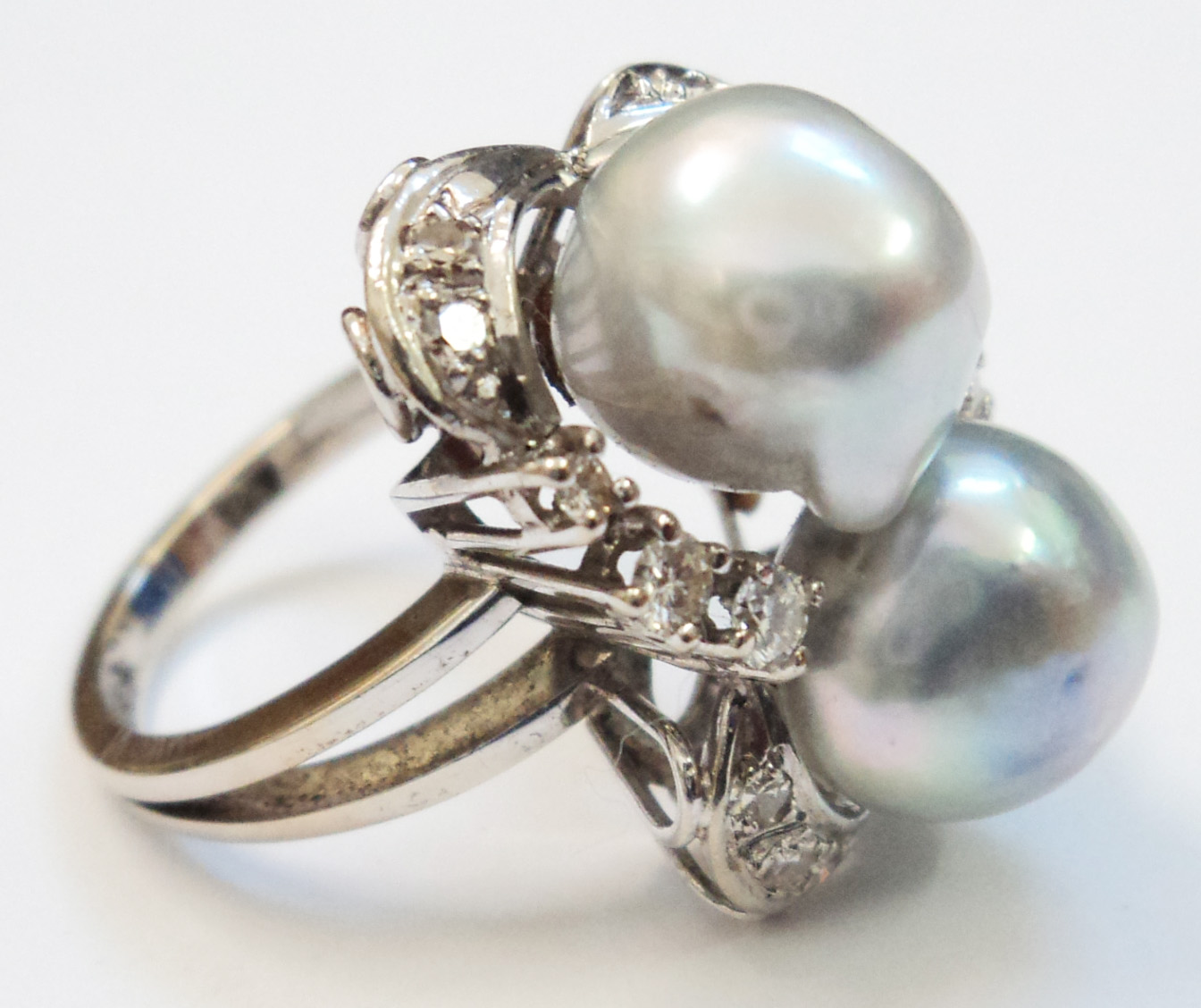 A marked .585 white gold dress ring, set with two large natural pale blue pearls within a diamond