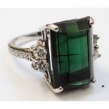 An 18ct. white gold ring set with large emerald cut oblong green topaz, with four flanking