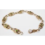 A gold reef knot link bracelet, set with seven peridots and lobster clasp