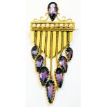 An Art Deco style yellow metal brooch with teardrop amethyst to open scroll top, a row of nine