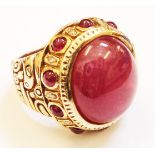 A marked 14k. ornate Eastern dress ring, set with large cabochon milky ruby within a beaded ruby and