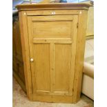 A 36" antique stripped pine corner cupboard with three shelves enclosed by a single panelled door