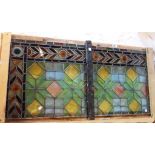 A pair of multicoloured stained glass window panels of geometric design, with stylised foliate