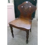 A pair of 19th Century oak hall chairs with carved crowns and shield motifs to shaped backs and