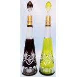 A pair of 17" Bohemian cut glass conical shaped decanters with stoppers, one red the other green,