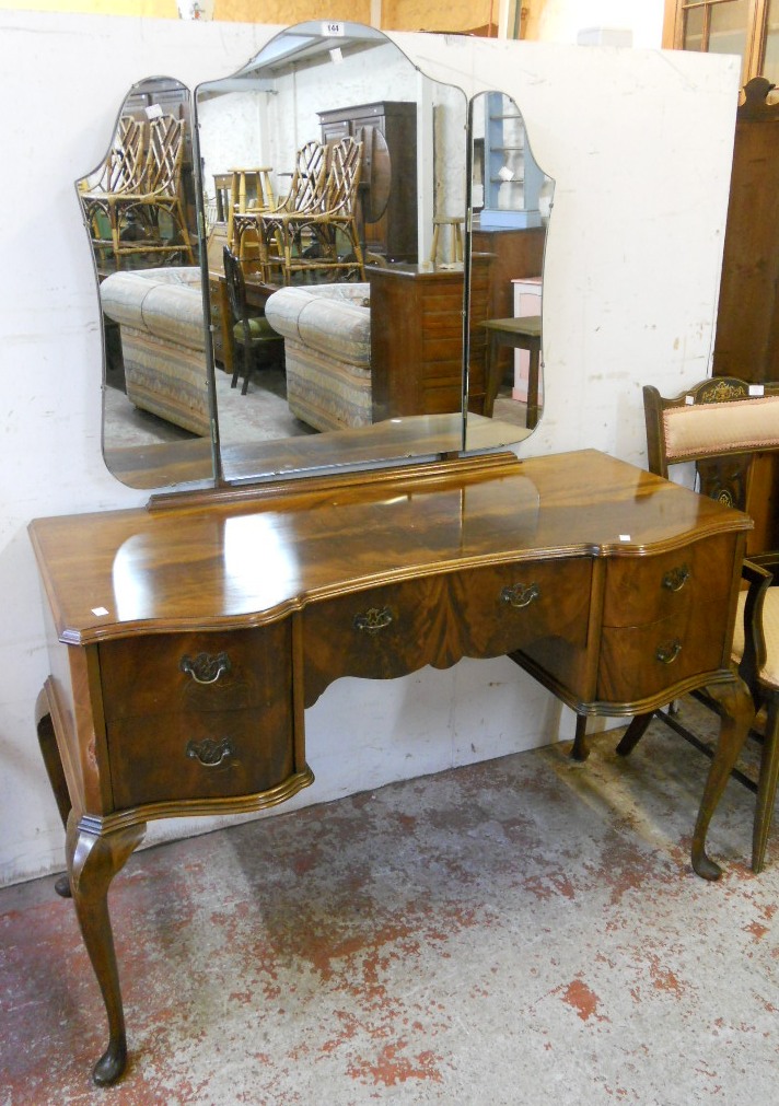 A 4' 20th Century book matched flame mahogany veneered serpentine front knee hole dressing table,