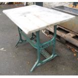 A marble table top set on a painted metal Singer sewing table base