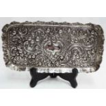 An 8" silver tray by Goldsmiths & Silversmiths Co. with profuse C-scroll and foliate decoration -