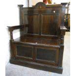 A 3' 1½" early 20th Century stained wood settle with shaped panelled back, flanking turned