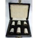 Six silver thimbles of varying design in fitted case