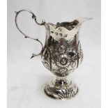 A George III silver cream jug with embossed floral decoration and S-scroll handle - London 1774