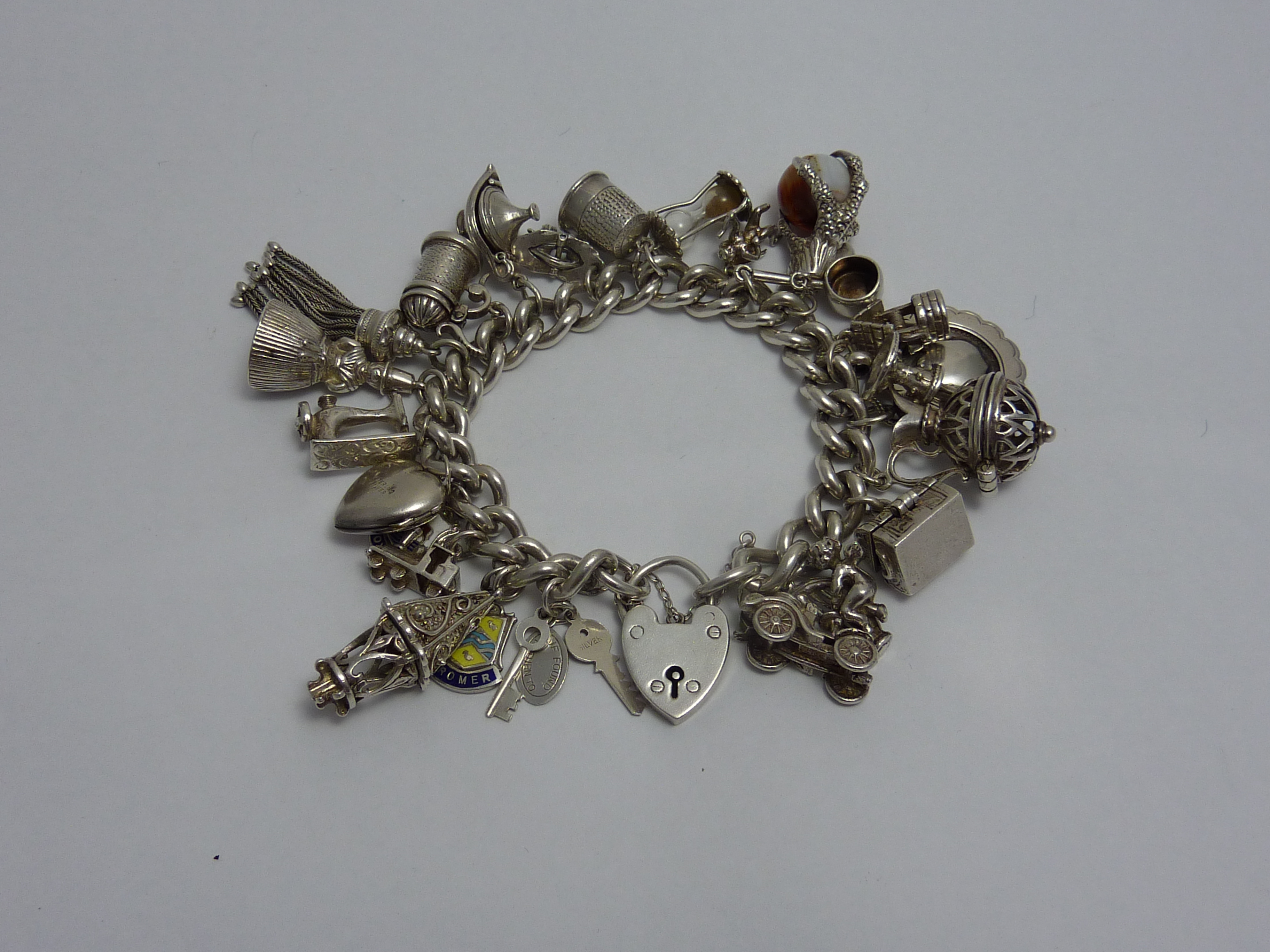 A VINTAGE SILVER CHARM BRACELET, comprising of twenty four novelty charms to the heart shape