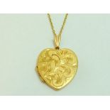 A 9CT GOLD LOCKET, of heart-shape, with engraved swirling pattern design to the fine link chain,