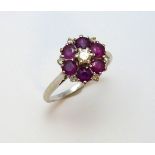 AN 18CT GOLD RUBY AND DIAMOND CLUSTER RING, the central brilliant cut diamond within a surround of