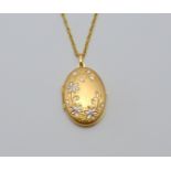 A 9CT GOLD LOCKET, of bi-metal colour and oval shape with foliage design, to the fancy link chain,