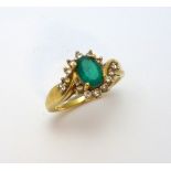 AN 18CT GOLD EMERALD AND DIAMOND RING, with central oval emerald within an abstract surround of