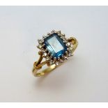 A 9CT GOLD ZIRCON AND DIAMOND RING, the rectangular shape blue zircon within a surround of single