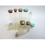 ELEVEN VARIOUS CUT GLASS DRESSING TABLE BOTTLES, some with silver and silver enamelled tops